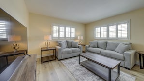 A living room with a sofa, coffee table, TV, and lamps. - Walk to Beach, Steps to Pool, Beach Chairs (Pompano Beach)