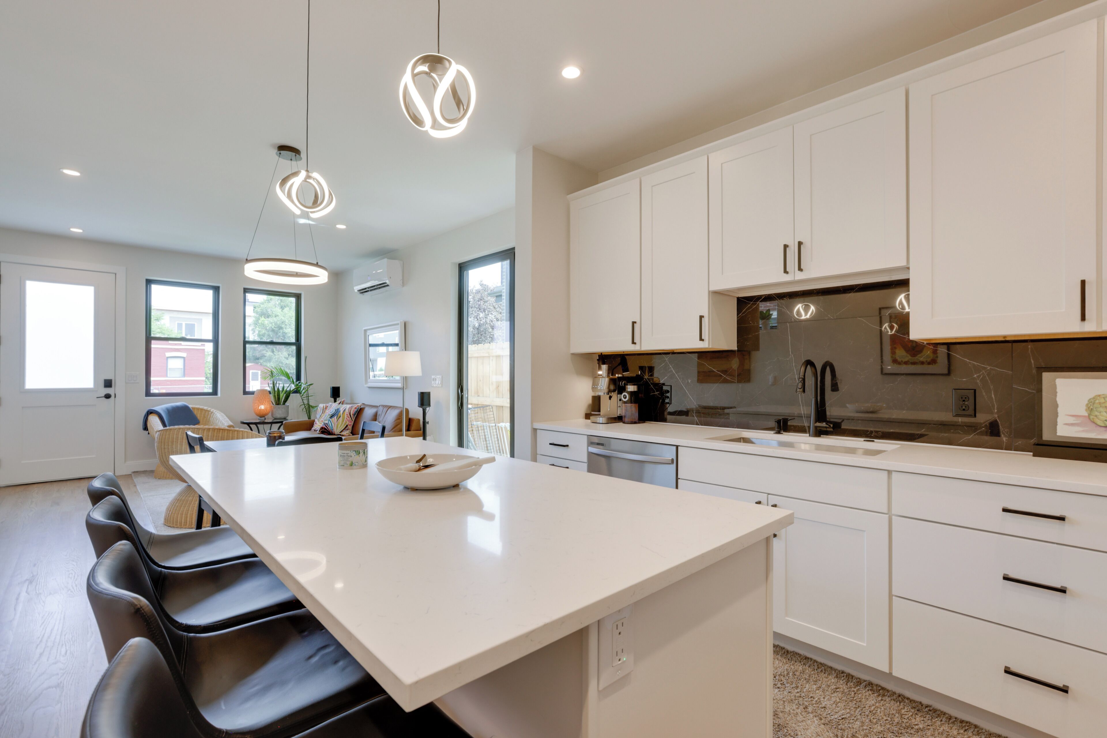 A modern kitchen with white cabinets, a large island, and pendant lighting.