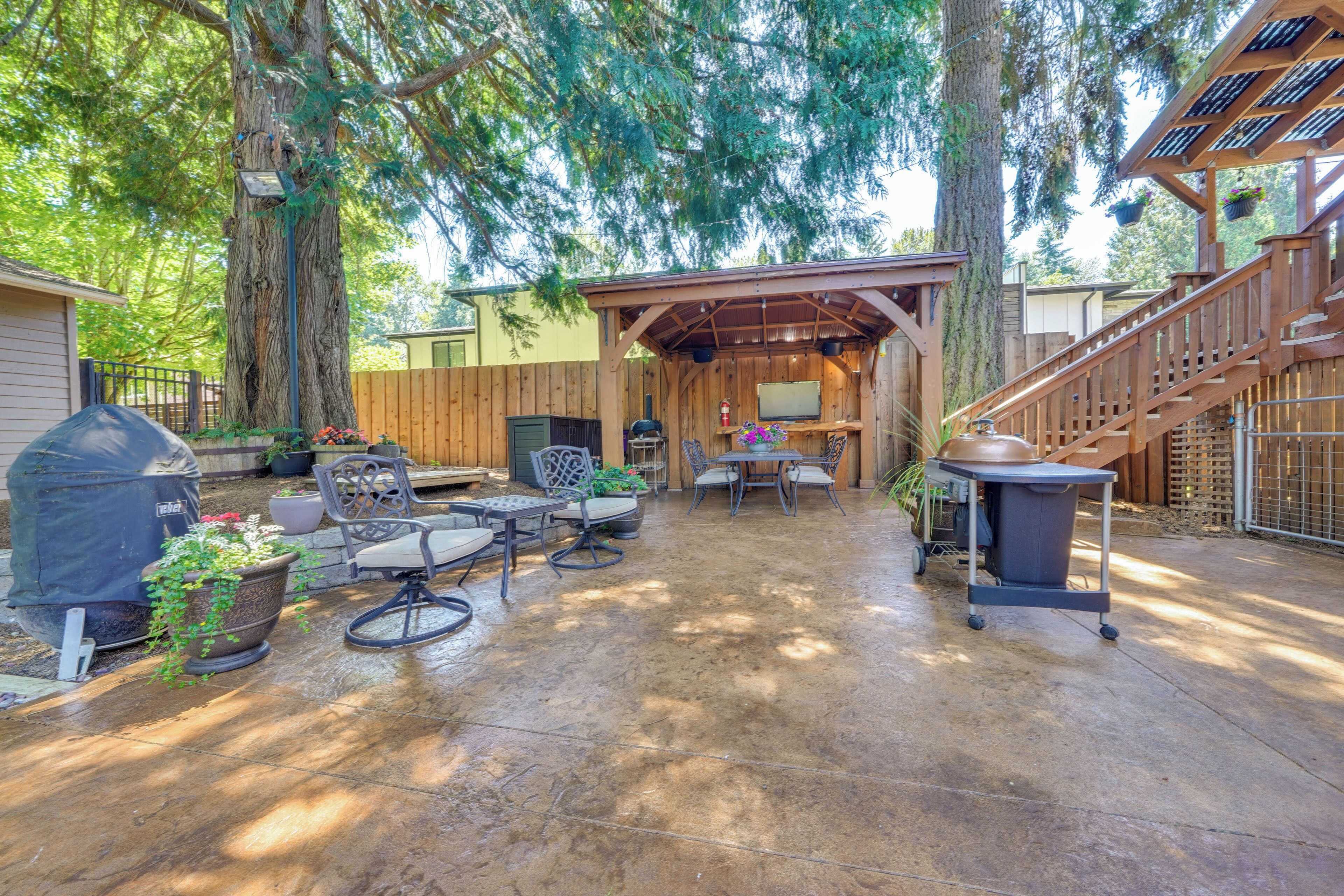 A covered patio area with outdoor furniture, a barbecue grill, and a wooden deck.