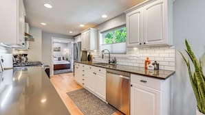 A modern kitchen with white cabinetry, stainless steel appliances, and a large island. - Seatac Getaway! Fully Fenced w/ Workspace (SeaTac)