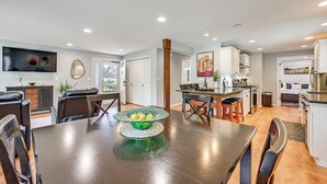 A modern kitchen with a dining area, a TV mounted on the wall, and a large window. - Seatac Getaway! Fully Fenced w/ Workspace (SeaTac)