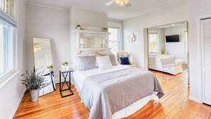 A bedroom with a large bed, a ceiling fan, a mirror, and a TV. - Walkable Oakley Neighborhood Home in Cincinnati! (Cincinnati)