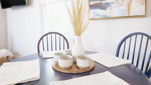 A dining table with a white vase and decorative grasses, surrounded by chairs and a wooden tray with cups. - Walkable Oakley Neighborhood Home in Cincinnati! (Cincinnati)
