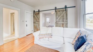 A white sofa with a striped blanket, a wooden floor, and a view through a window. - Walkable Oakley Neighborhood Home in Cincinnati! (Cincinnati)