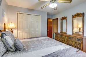 A bedroom with a bed, dresser, mirror, ceiling fan, and two doors. - Explore Baton Rouge! Cozy Retreat w/ Private Yard (Baton Rouge)