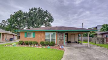 A single-story house with a brick facade, green shutters, and a covered porch.