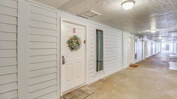 A hallway with a white door, a welcome mat, and a light fixture on the ceiling.