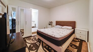 Ein Schlafzimmer mit Bett, Nachttischen, Fernseher, Kleiderschrank und Spiegel.