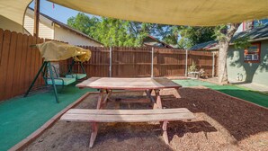 Ein Garten mit einem Holztisch, einer Schaukel und einem schattigen Bereich.