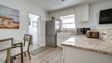 A kitchen with white cabinets, a stainless steel refrigerator, a microwave, and a granite countertop.