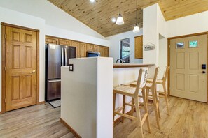A kitchen with wooden cabinets, a refrigerator, and a bar area with chairs. - Outdoor Oasis w/ Fire Pit & Grill! Torreon Escape (Show Low)