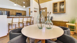 A modern kitchen with wooden cabinets, a central island, and a dining area with a round table and grey sofas. - Outdoor Oasis w/ Fire Pit & Grill! Torreon Escape (Show Low)