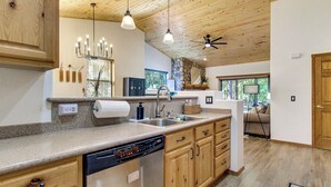 A kitchen with wooden cabinets, a dishwasher, a sink, and pendant lighting. - Outdoor Oasis w/ Fire Pit & Grill! Torreon Escape (Show Low)