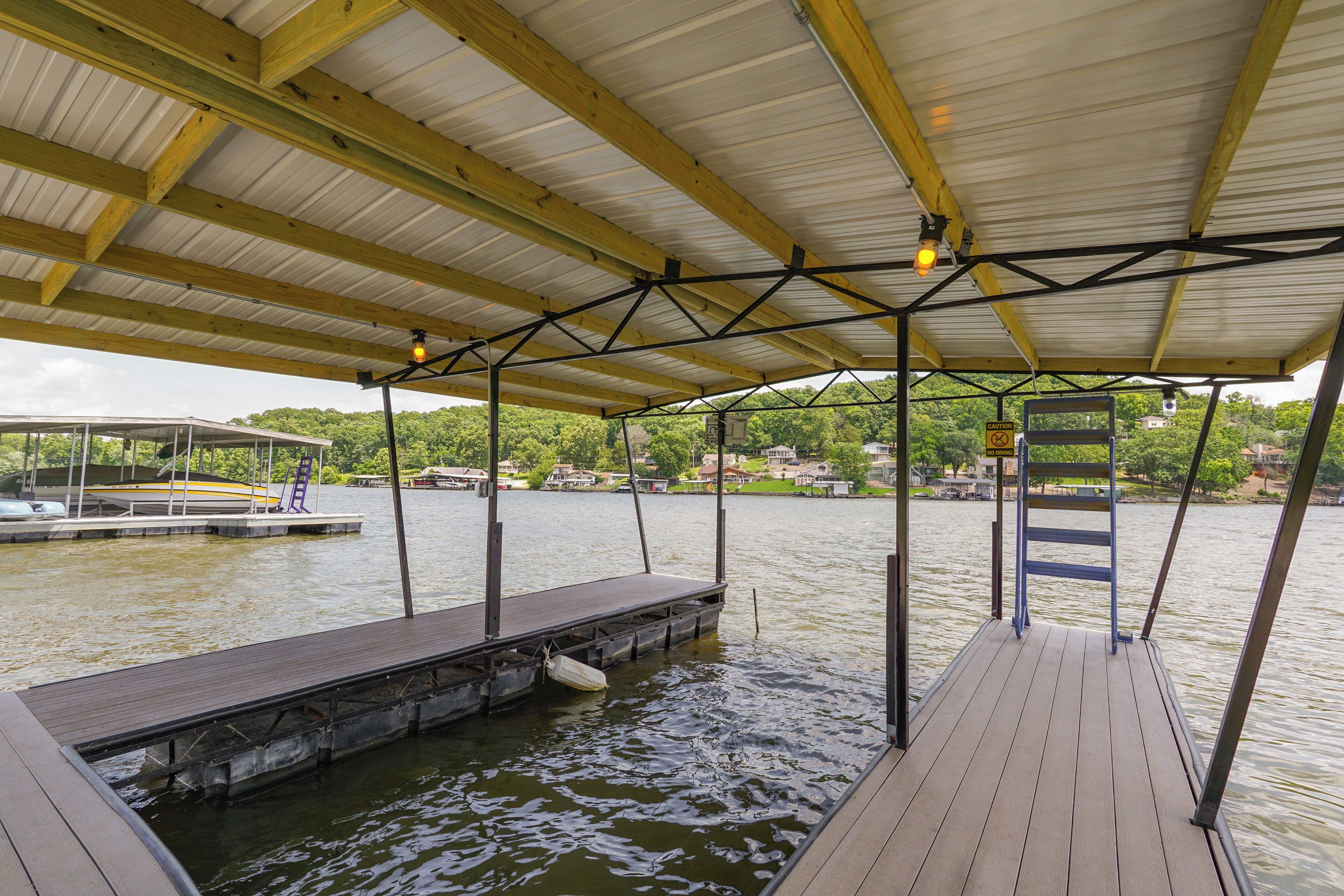 A covered dock with a wooden deck, metal beams, and a ladder.