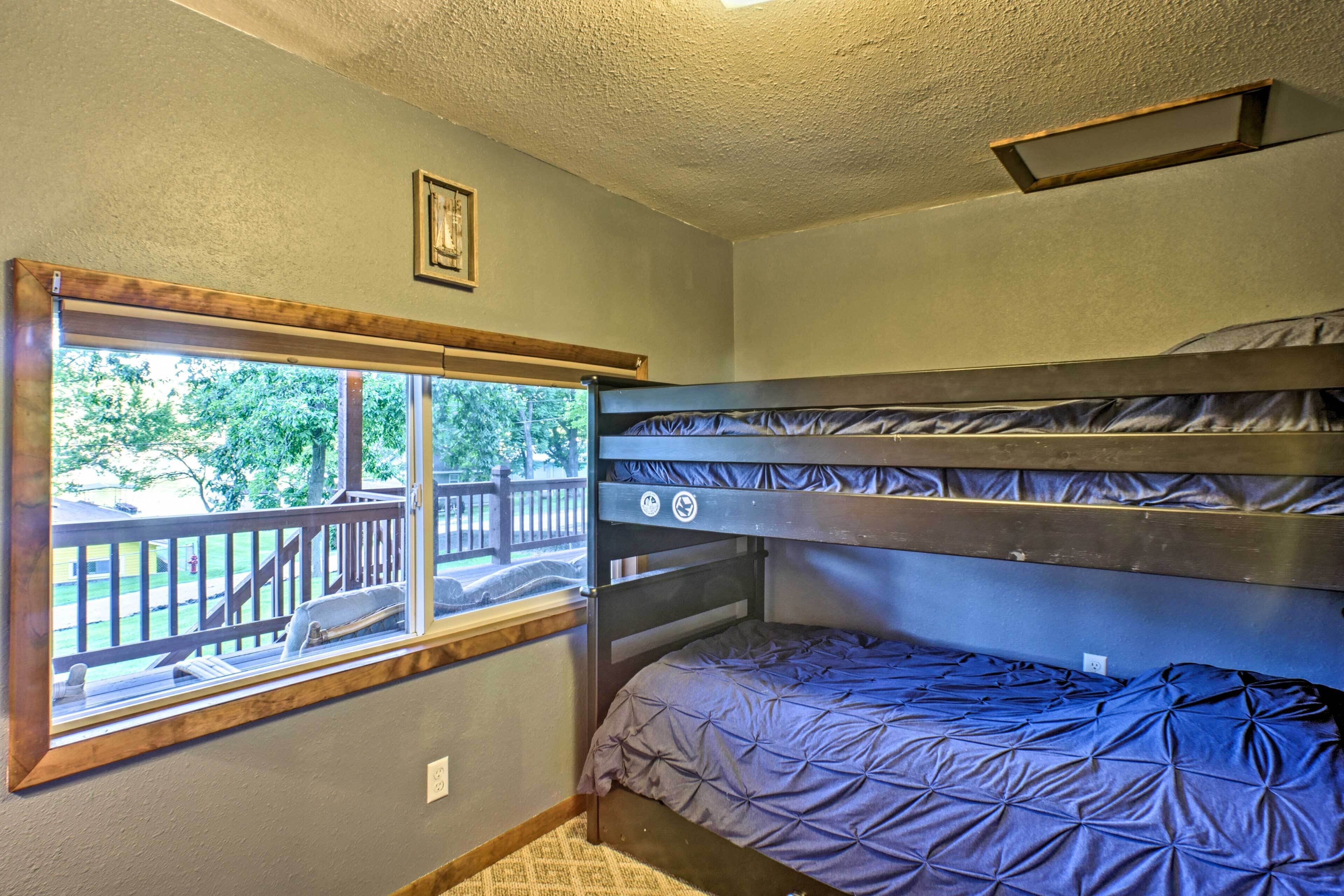 A bunk bed room with a window overlooking a deck.