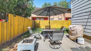 A backyard patio with a table and chairs, a covered grill, and a yellow fence. - Work, Play & Explore w/ Ease! Dtwn Meridian Apt (Meridian)