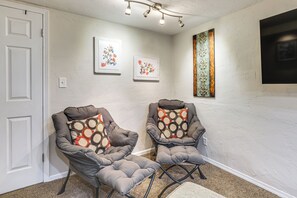 A room with two grey armchairs with patterned cushions, a white door, and a wall with two framed floral artworks. - Work, Play & Explore w/ Ease! Dtwn Meridian Apt (Meridian)