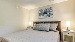 A bedroom with a bed, two bedside tables, a nightstand, a wall-mounted painting, and a ceiling light. - Work, Play & Explore w/ Ease! Dtwn Meridian Apt (Meridian)