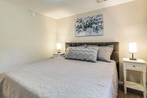 A bedroom with a bed, two bedside tables, a nightstand, a wall-mounted painting, and a ceiling light. - Work, Play & Explore w/ Ease! Dtwn Meridian Apt (Meridian)