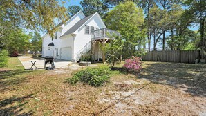 A two-story house with a covered porch, a barbecue grill, and a small patio area. - Near Eats, Shops, Golf & Beach: Oak Island Suite! (Oak Island)
