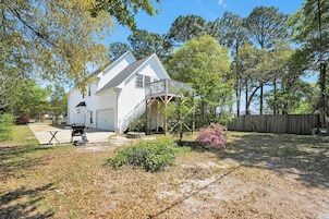 A two-story house with a covered porch, a barbecue grill, and a small patio area.