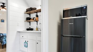 A kitchen with white cabinetry, a stainless steel refrigerator, and a wooden shelf with kitchen items. - Near Eats, Shops, Golf & Beach: Oak Island Suite! (Oak Island)