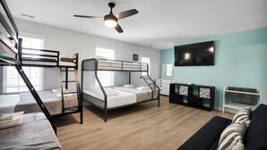 Ein Zimmer mit Etagenbetten, Deckenventilator, Flachbildfernseher, einer Couch und einem kleinen Schrank.