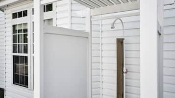 A white exterior with a wooden door, a window, and a metal showerhead.