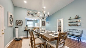 A dining area with a long wooden table, six chairs, a chandelier, and wall decorations. - Day Trips to Gsmnp! Golfers Oasis in Franklin (Franklin)