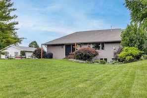 A single-story house with a covered porch, a lawn, and a small garden.