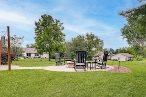 A patio area with outdoor furniture, a fire pit, and a stone fire ring.