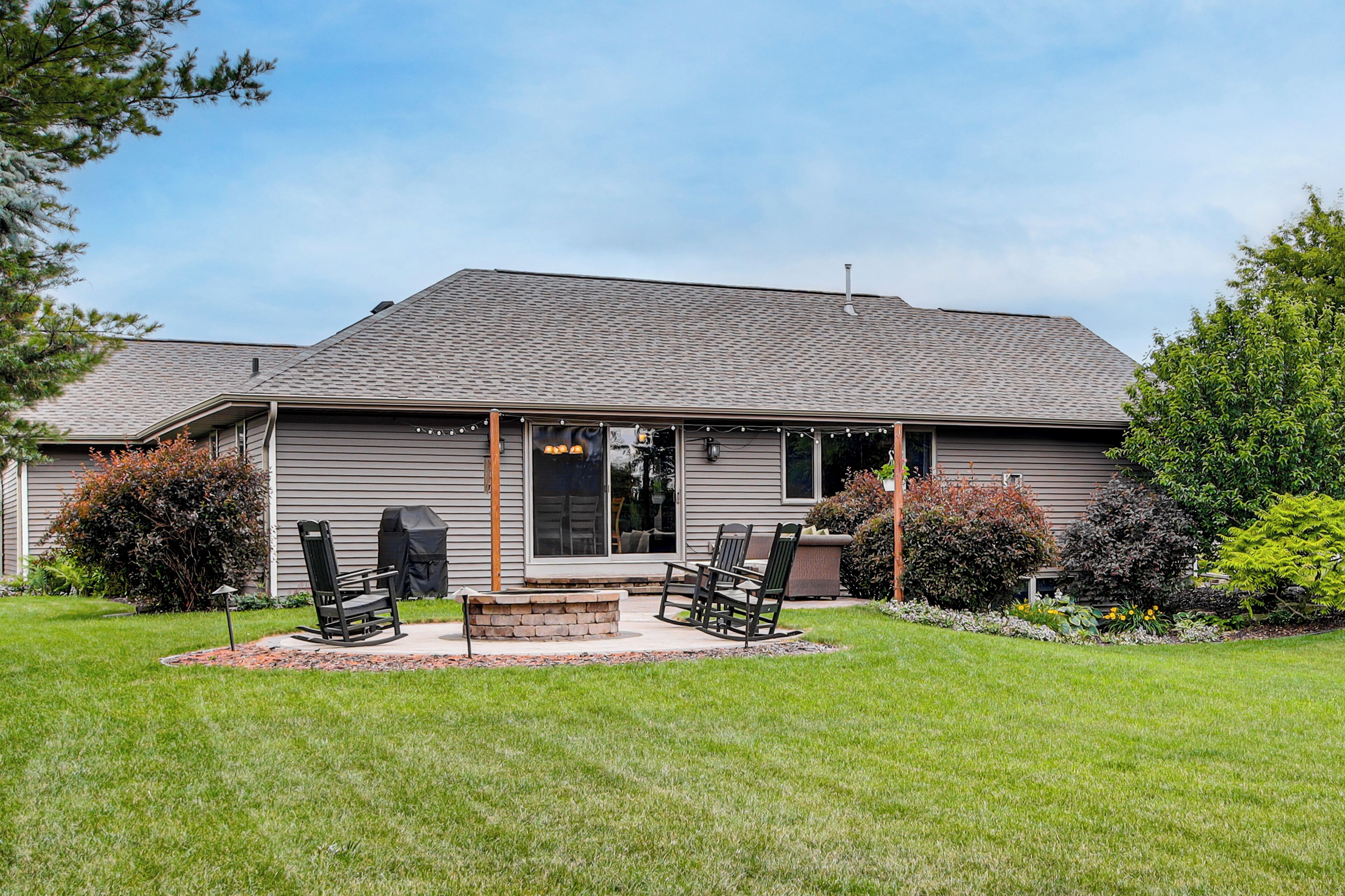 A house with a covered patio, outdoor seating, and a well-maintained lawn.