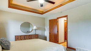 A bedroom with a bed, a wooden headboard, a ceiling fan, a mirror, and a door leading to another room. - Family Home w/ Patio, 9 Mi to Downtown Appleton (Greenville)