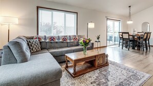 Ein Wohnzimmer mit einer Eckcouch, einem Couchtisch und einem Essbereich mit Tisch und Stühlen.