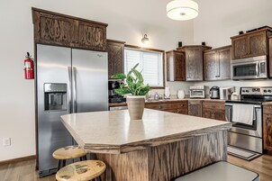 Una cocina moderna con una isla central, armarios de madera, electrodomésticos de acero inoxidable y un extintor.