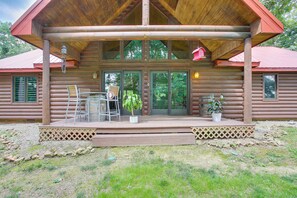 A log cabin with a covered porch, a dining area with chairs and a table, and a potted plant. - Peaceful Cabin Between Nashville & Bowling Green! (Portland)