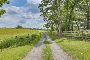 A gravel path flanked by a wooden fence and trees, leading through a grassy field. - Peaceful Cabin Between Nashville & Bowling Green! (Portland)