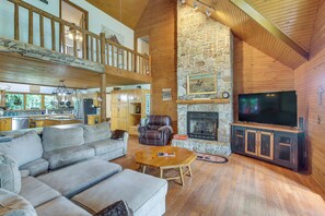 A spacious living room with a stone fireplace, a television, and a leather chair. - Peaceful Cabin Between Nashville & Bowling Green! (Portland)