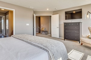 Un dormitorio con cama, cómoda, televisor y una silla.