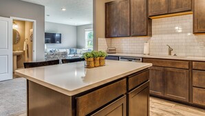 A modern kitchen with wooden cabinets, a central island, and pendant lighting. - Relax Poolside! Retreat 11 Mi to Eagle Creek Park (Whitestown)