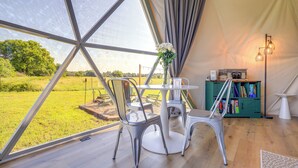 A tent with a dining area, a bookshelf, and a view of the outdoors.