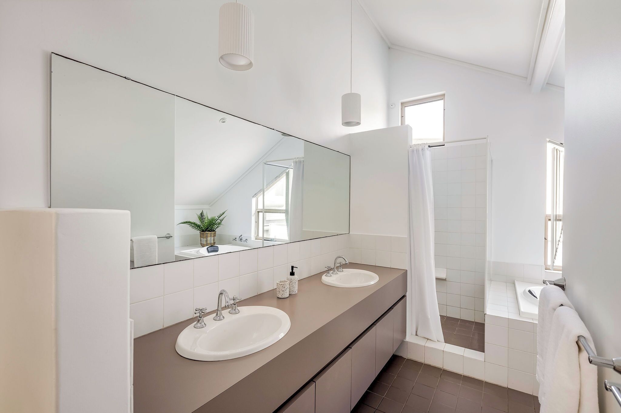 Een moderne badkamer met twee wastafels, een grote spiegel en een douchecabine.