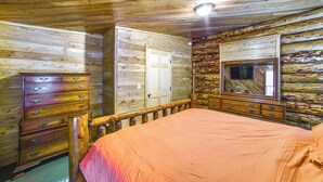 A wooden cabin interior with a bed, dresser, and mirror.