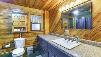 A wooden cabin bathroom with a toilet, sink, vanity, and mirror.