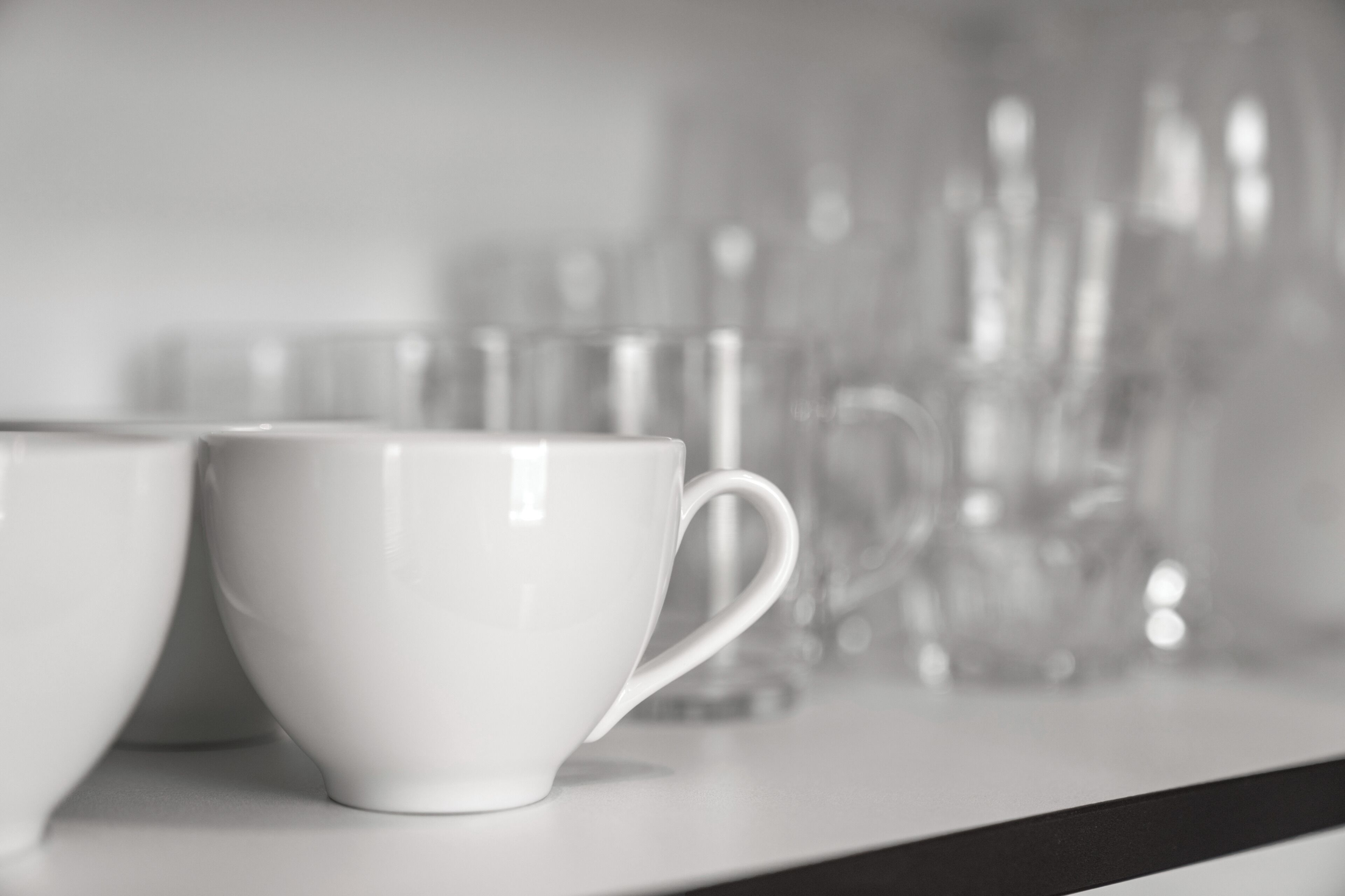 A row of white cups and glasses on a table.