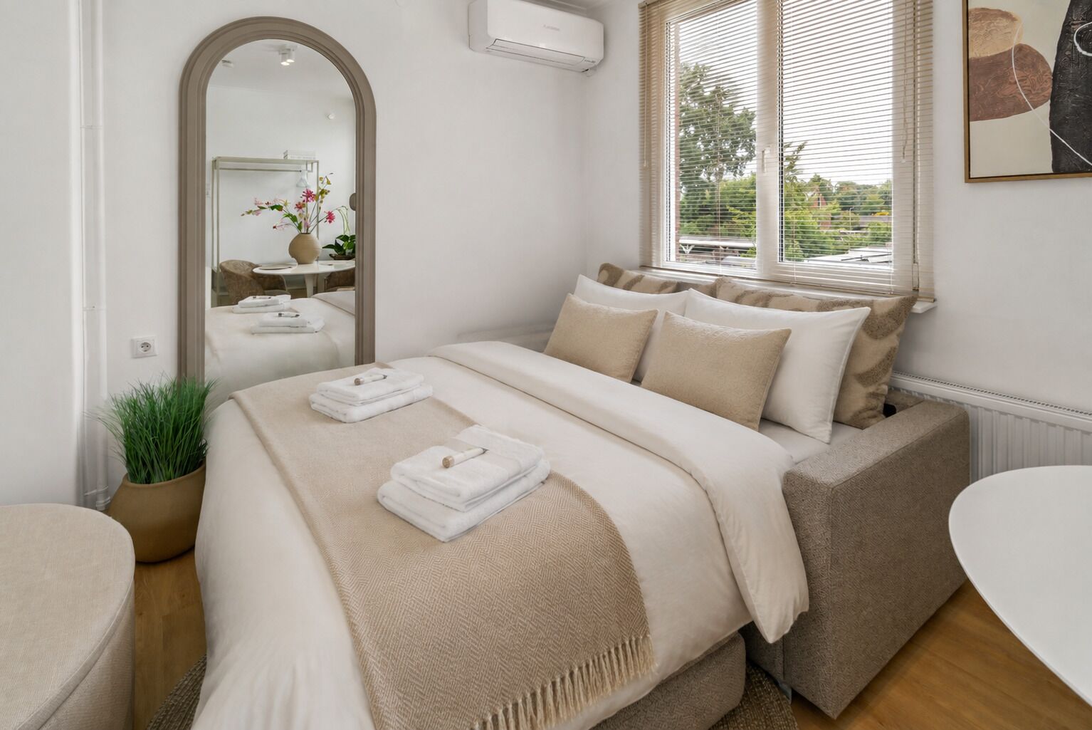 Een moderne slaapkamer met een bed, nachtkastje en een groot raam.