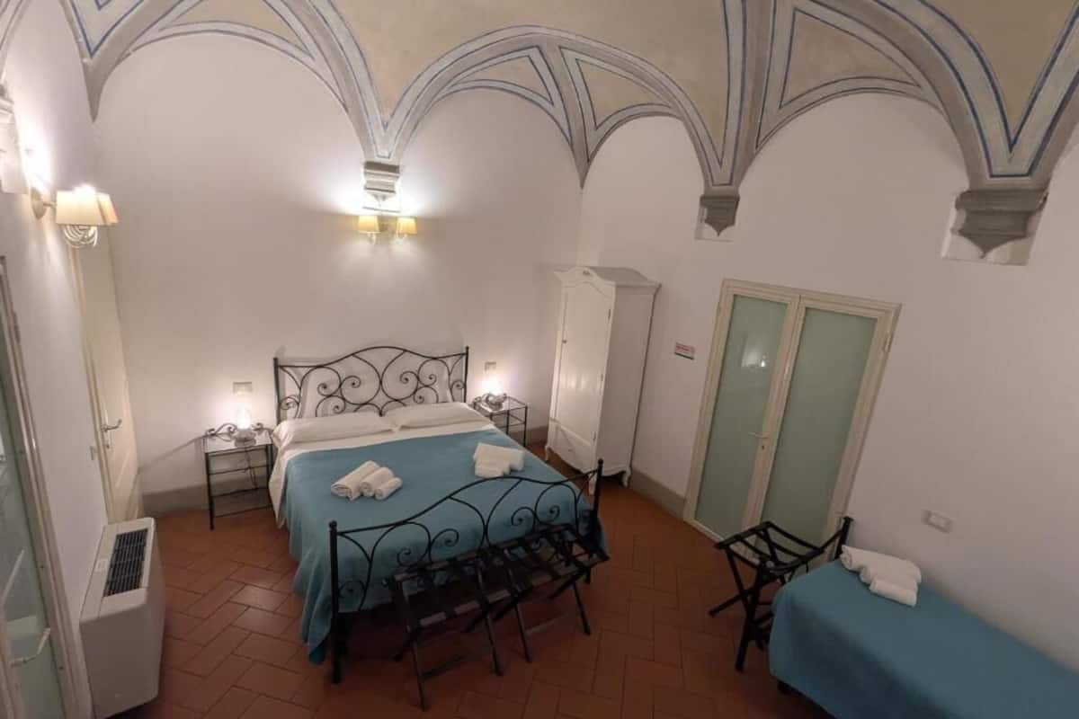 A bedroom with a bed, a chair, a wardrobe, and a table.