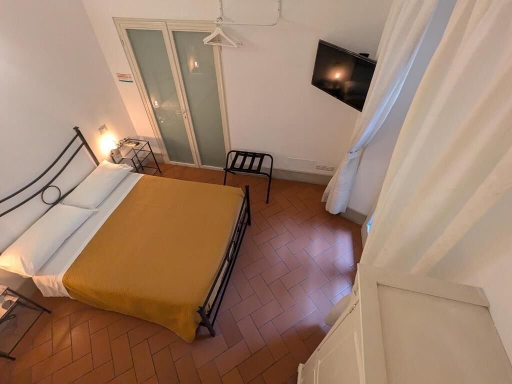 Une pièce comprenant un lit, une chaise, un téléviseur et une porte coulissante.