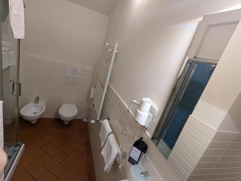 Een badkamer met een hygiëneslot, toilet en een spiegel.