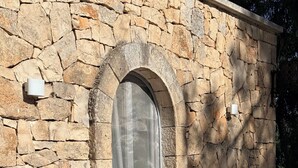 Ein Steinhaus mit einem Fenster und einer kleinen Außenfläche.